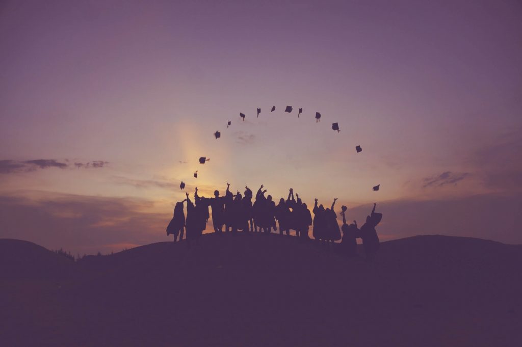 Silhouette of fresh graduates throwing their hats into the air simbolizing hope for comfortably landing a job