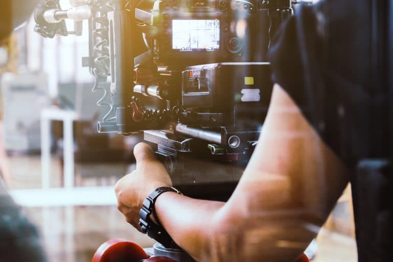 Close-up photo of high-end camera equipment being manned by an unrecognizable cameraman while working in the entertainment industry