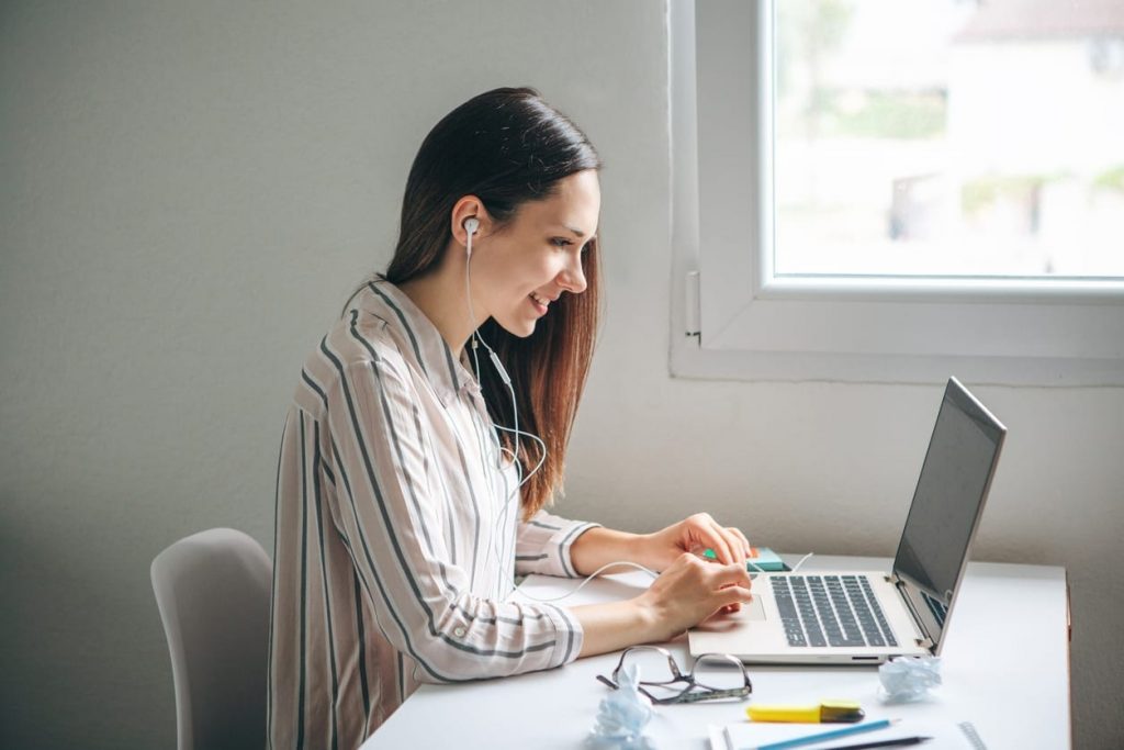 happy woman listening to a podcast on her laptop and not being bothered by bullying at work