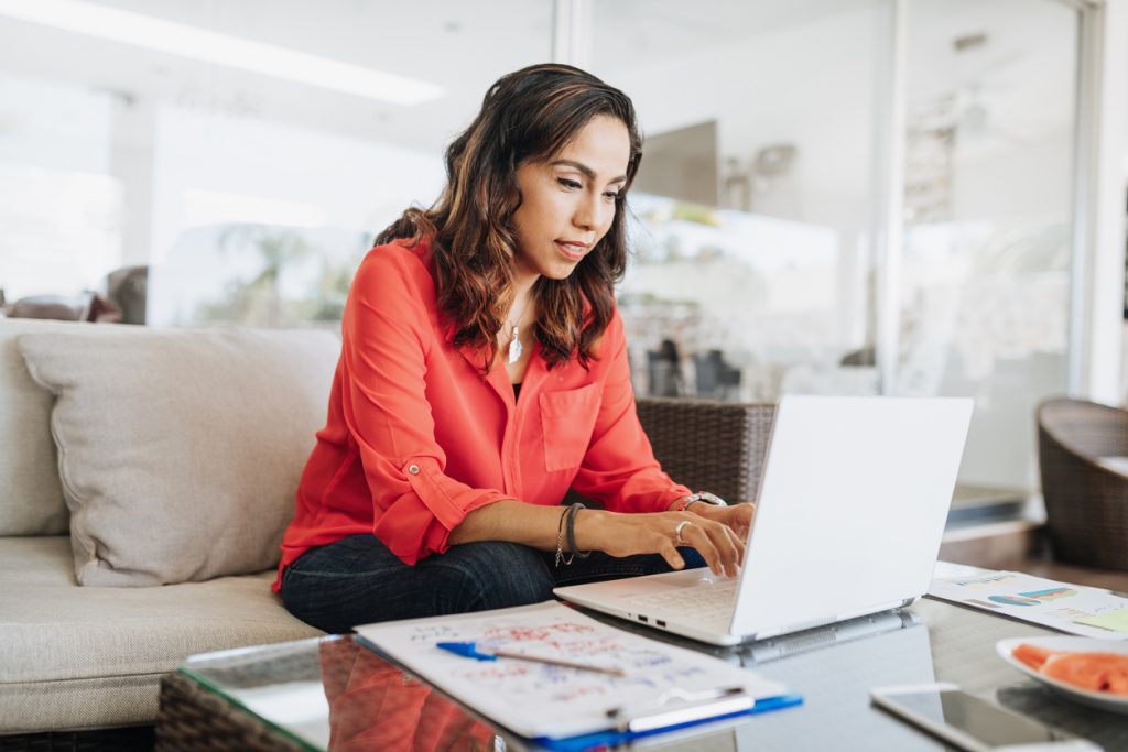 Mature Latina businesswoman looking for data entry jobs on her laptop at home