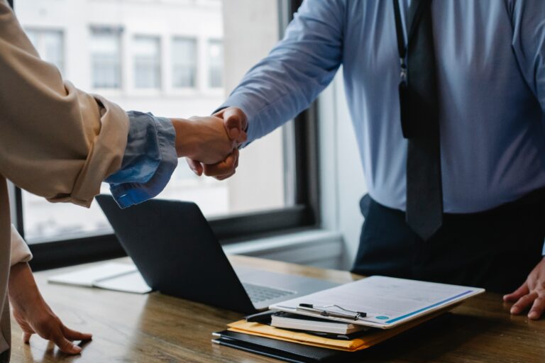 two people shaking each others hands over a signed contract