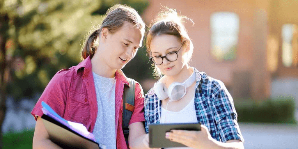 Two teen students viewing a tablet device.